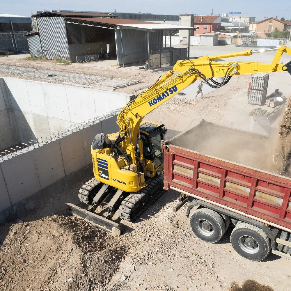 Komatsu-grävmaskin som lastar grus på en lastbil