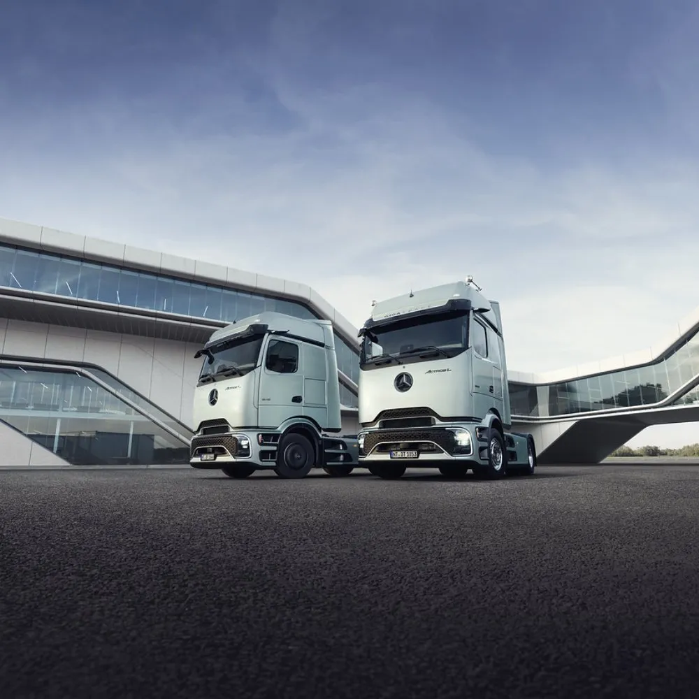 Två vita Mercedes-Benz-lastbilar framför en modern byggnad